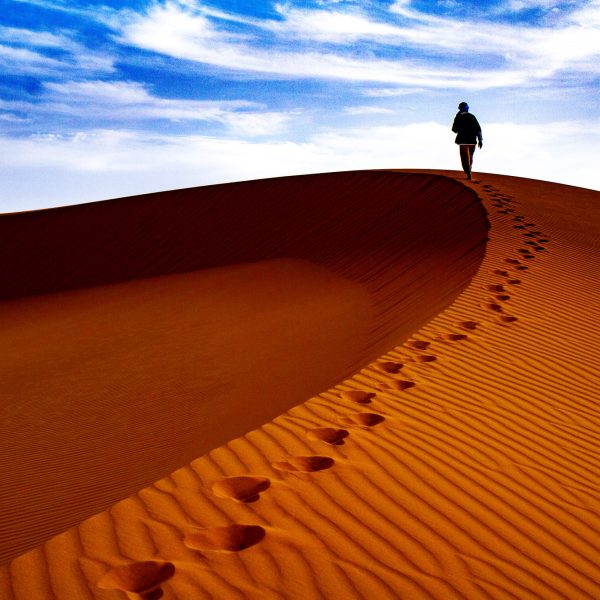 Homme marchant sur la crête d'une dune dans le sahara marocain